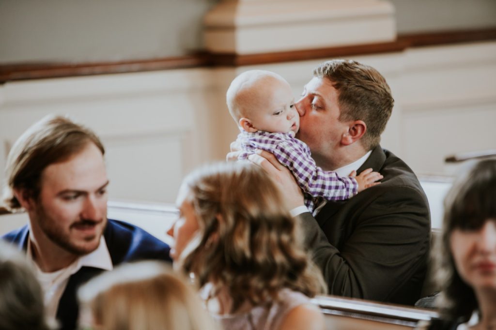 man kisses baby on cheek before start of wedding in meridian street united methodist church
