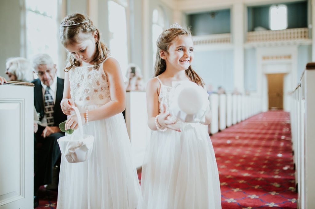 two flower girls in bright sunlight walked down the aisle