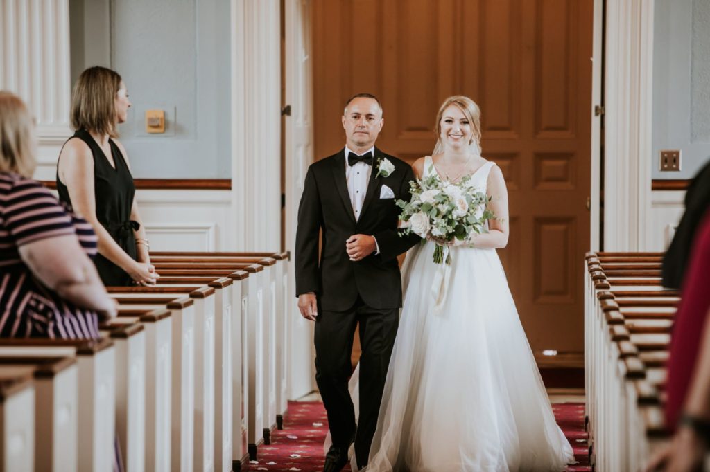 father of the bride and bride walk down the aisle at meridian street united methodist church