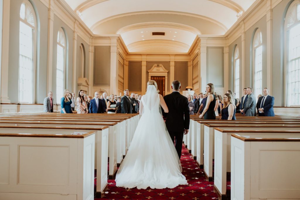 wide shot of bride walking down the aisle at meridian street united methodist church from behind