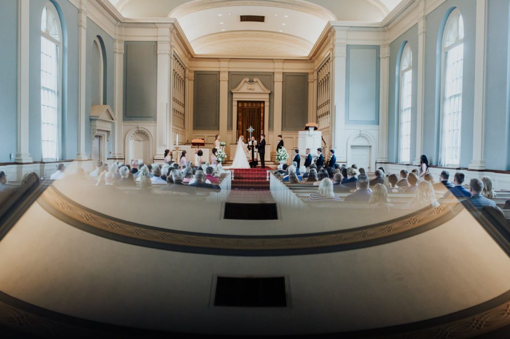 wide shot of meridian street united methodist church during wedding with reflection of ceiling cast over the guests seated in the pews