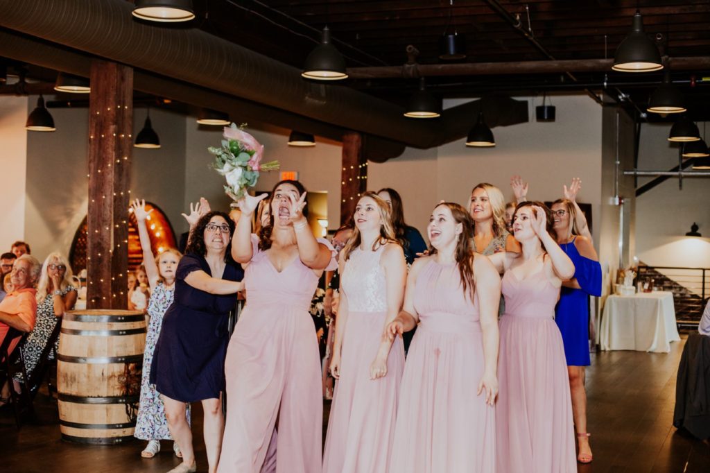 women scramble to catch bouquet during a Tinker House Wedding