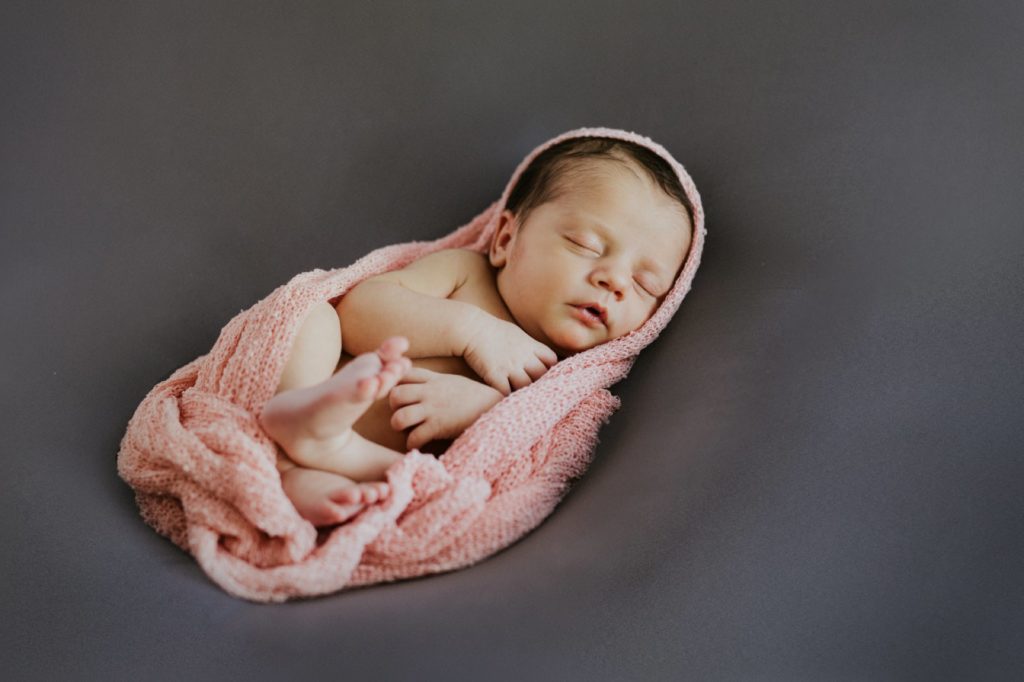 baby girl in pink blanket on gray backdrop for Noblesville Newborn Photography
