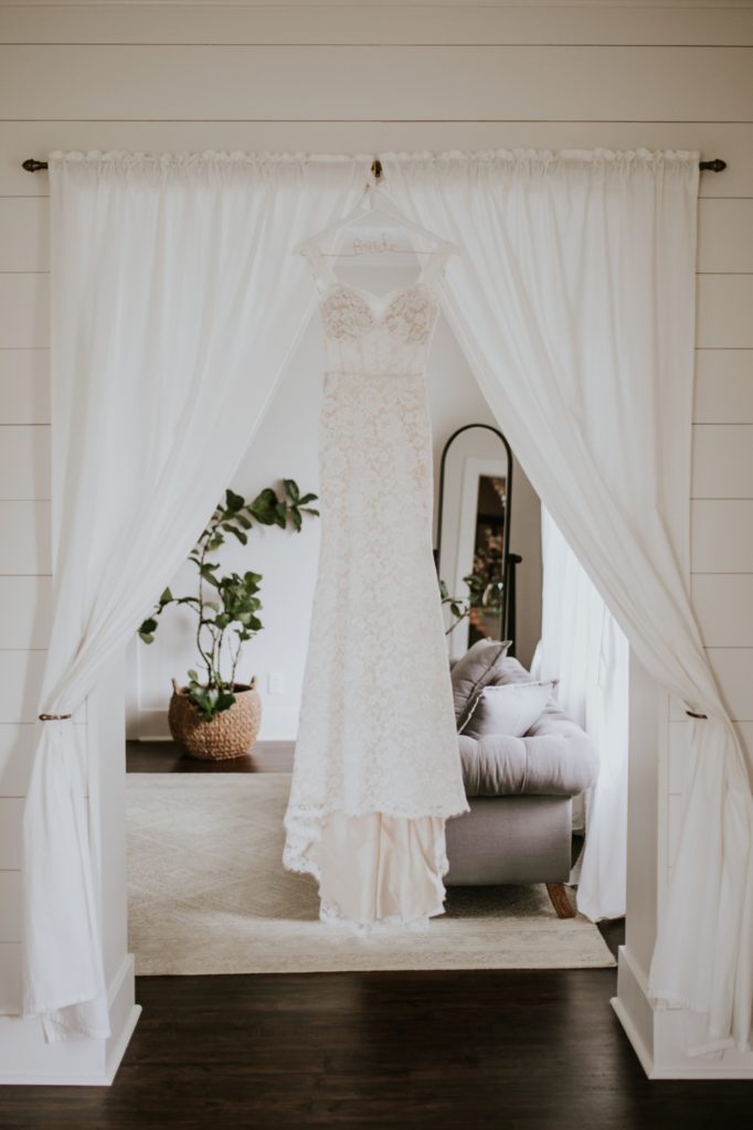 wedding dress hanging in curtained arch at mustard see gardens for Noblesville Wedding Photography