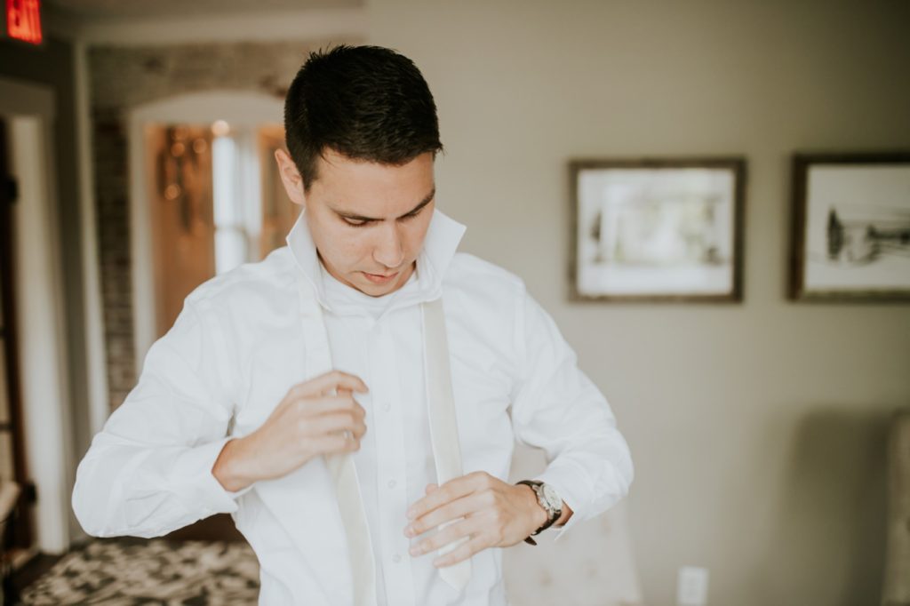 groom gets dressed for wedding at mustard seed gardens