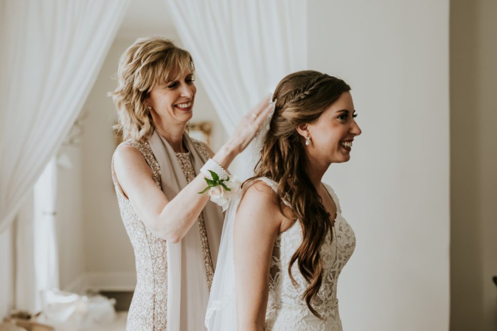 mother of bride puts veil into bride's hair at mustard seed gardens