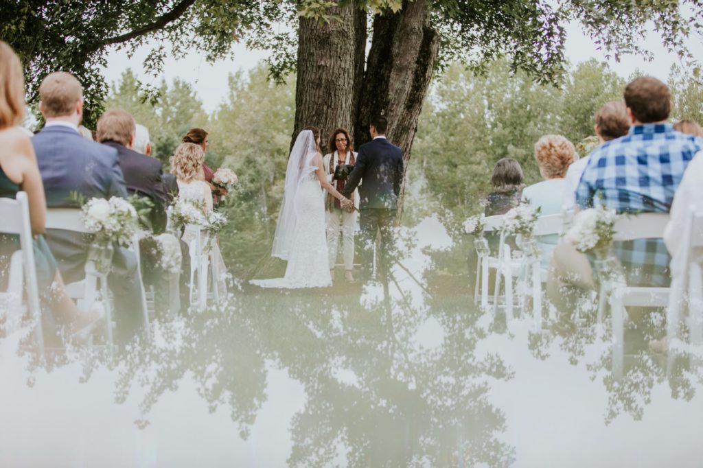 reflections of the sky on the bride and groom during their ceremony at mustard seed gardens