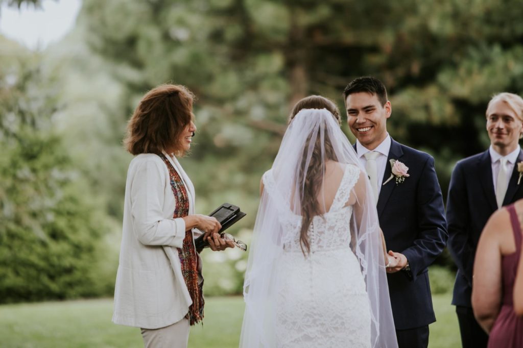 groom smiles and laughs during wedding ceremony at mustard seed gardens for Noblesville Wedding Photography