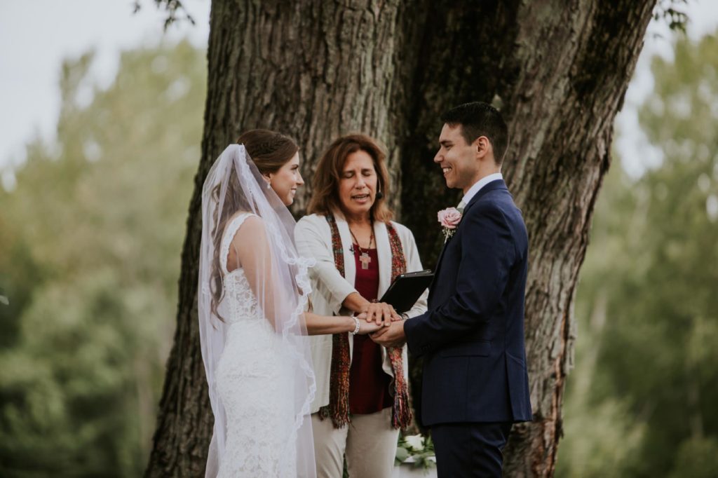 officiant blesses rings during ceremony at mustard seed gardens