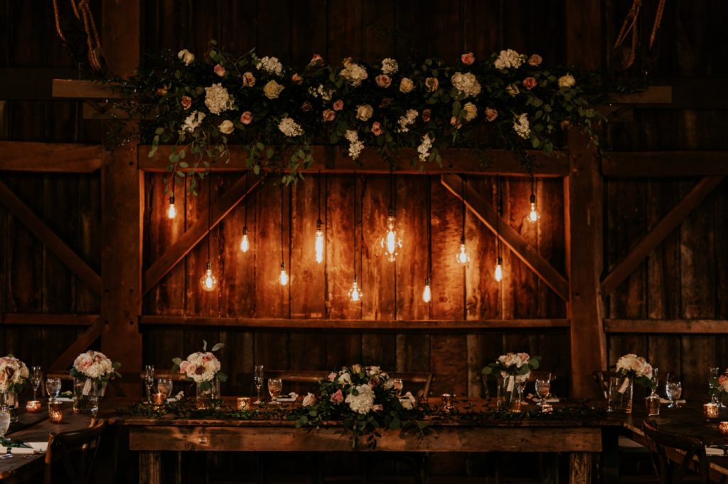 lights and flowers on the wooden wall of a barn at mustard seed gardens