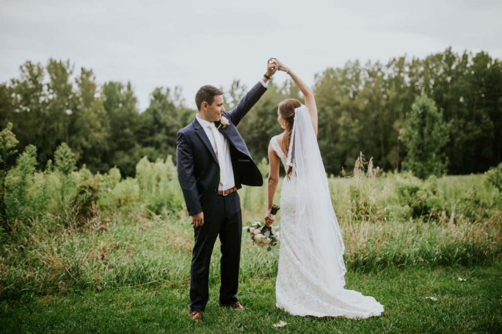 bride and groom dance in front of a field of grass during their Noblesville Wedding Photography