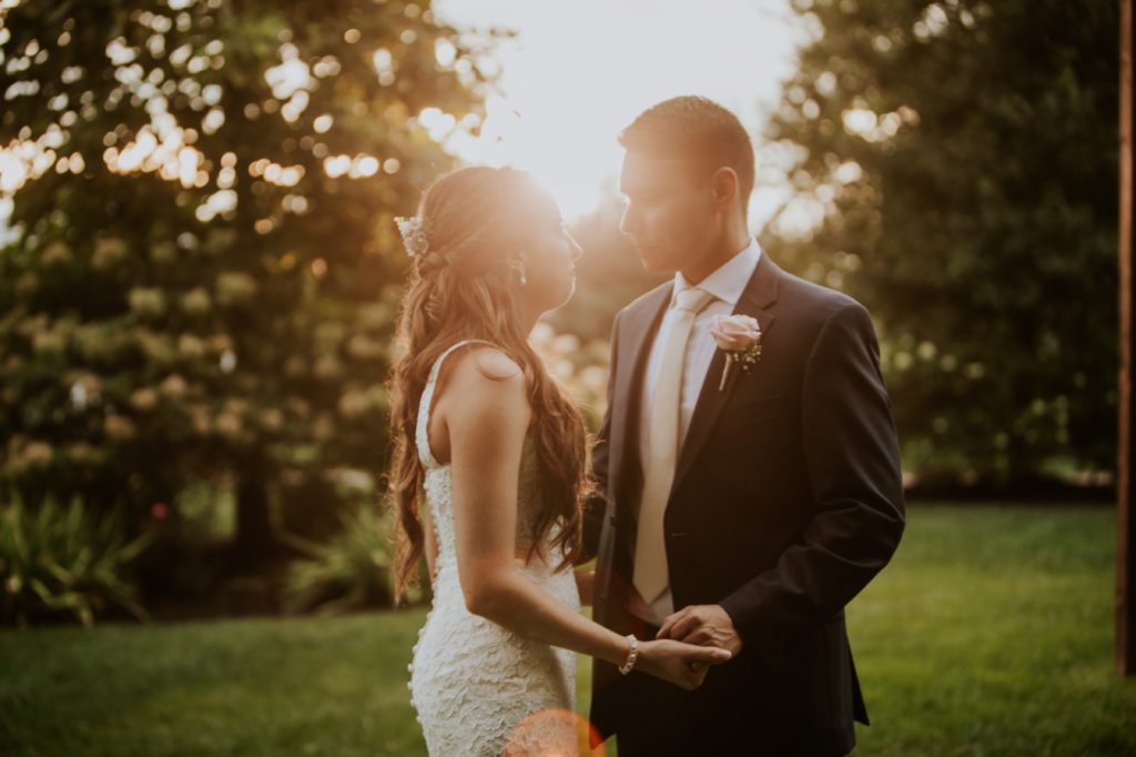 bride and groom hold hands and look at each other at sunset for Noblesville Wedding Photography at mustard seed gardens