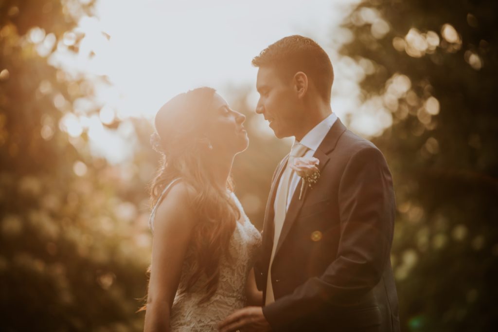 bride and groom are about to kiss at sunset in orange tone photo at mustard seed gardens for Noblesville Wedding Photography