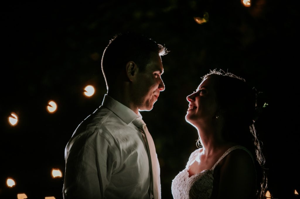 bride and groom look at each other and smile during night shot at mustard seed gardens for Noblesville Wedding Photography