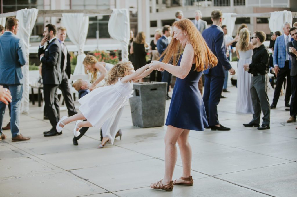 a red haired woman dances with a flower girl at a Regions Tower wedding