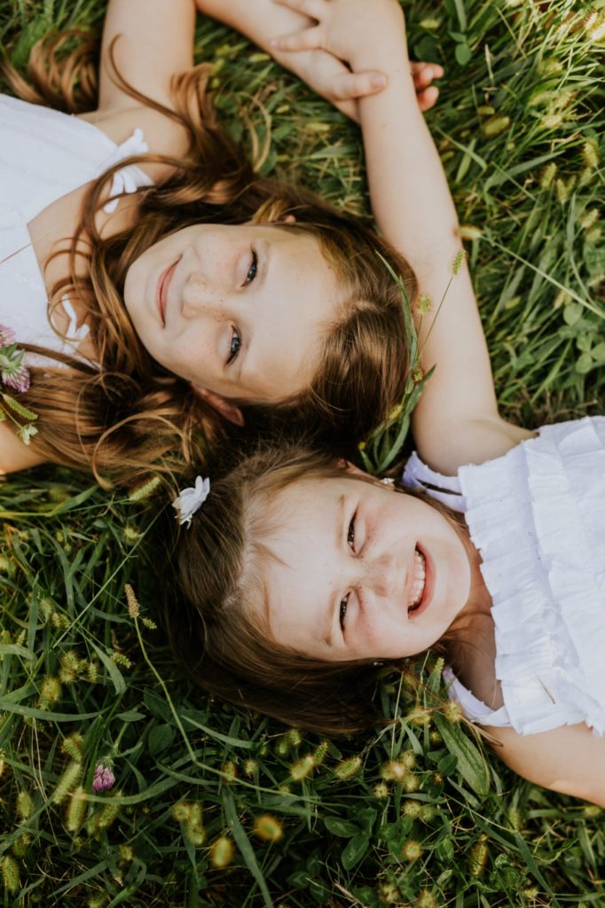 two young girls lay in the grass and smile in this Tuttle Orchards Family Photo session