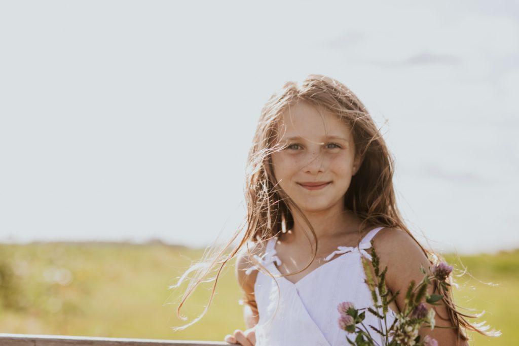 a young girl smiles while backlit by the sun in this Tuttle Orchards Family Photo session