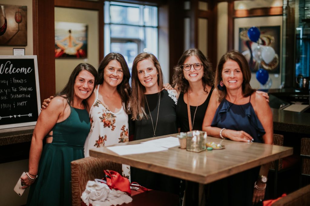 a group of women hug and smile for a photo in Indianapolis at Tastings Wine Bar and Bistro