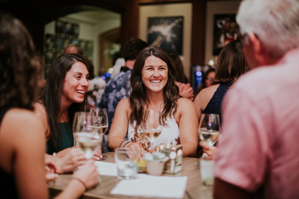 a group of women laugh and smile at a table at Tastings Wine bar for downtown indy event photography