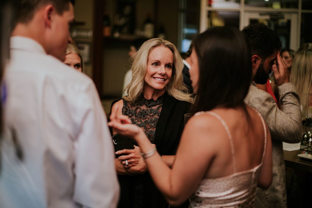 a blonde woman smiles while talking to people at Tastings Wine Bar