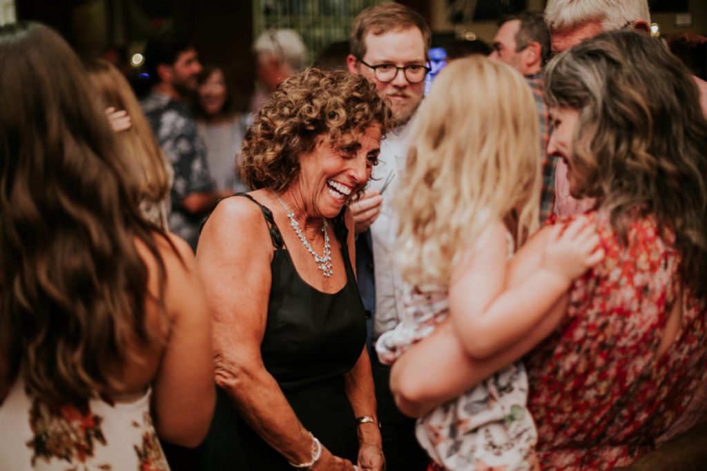 a woman with curly hair laughs in the middle of a crowd at Tasting Wine Bar