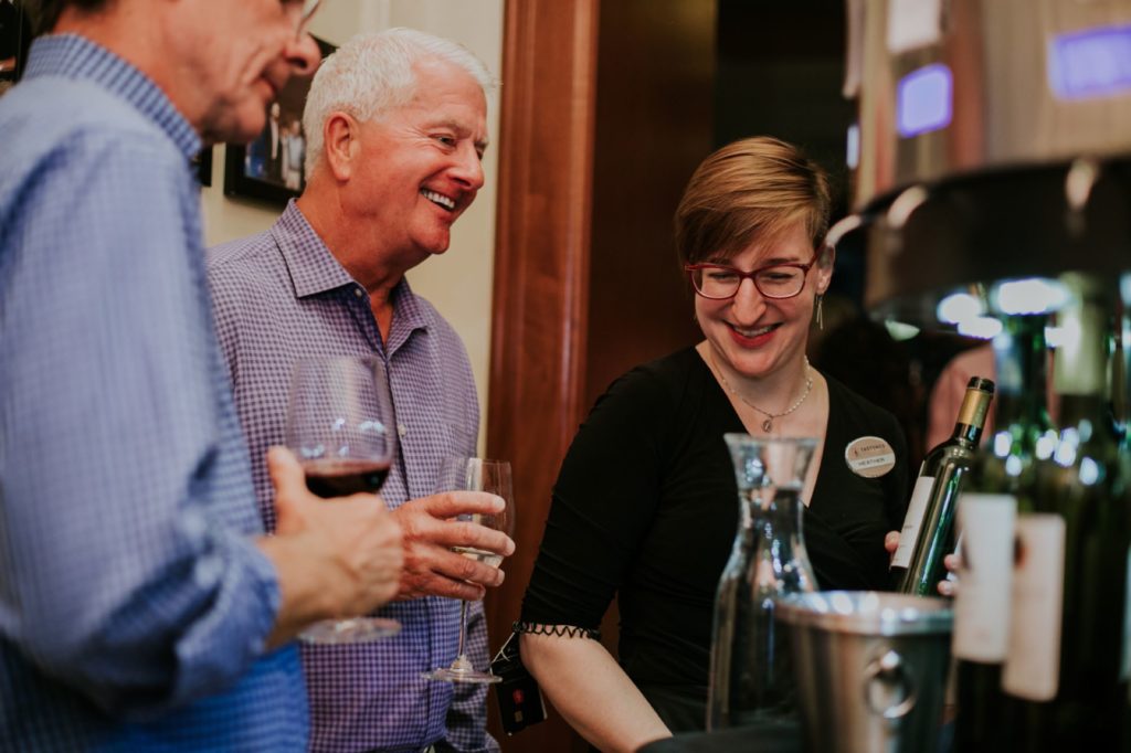a server shows two men how to use the wine machine at Tastings Wine Bar and Bistro