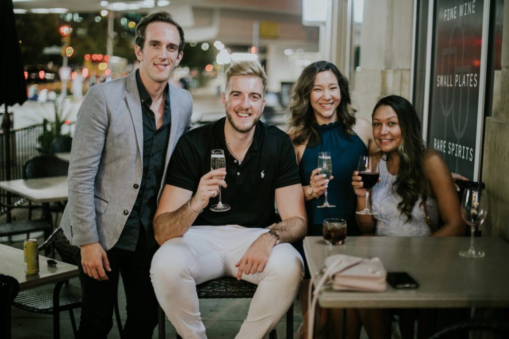a group of people pose outside Tastings Bar and Bistro in downtown indianapolis with wine glasses for an event photographer