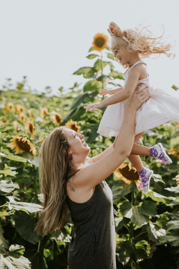 mom throws daughter into air while surrounded by flowers at tuttle orchard