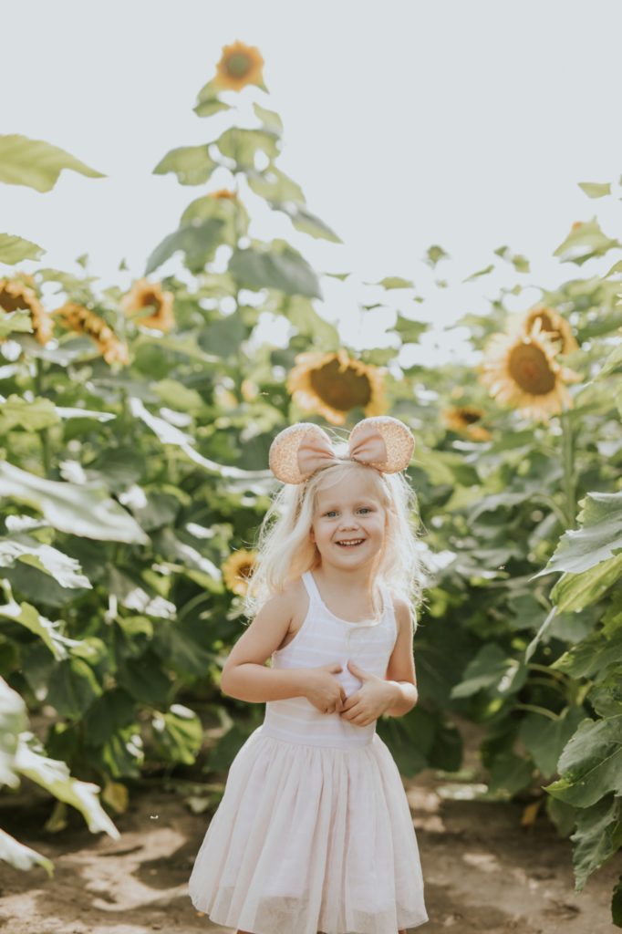 blonde toddler girl laughs in flower field at tuttle orchard