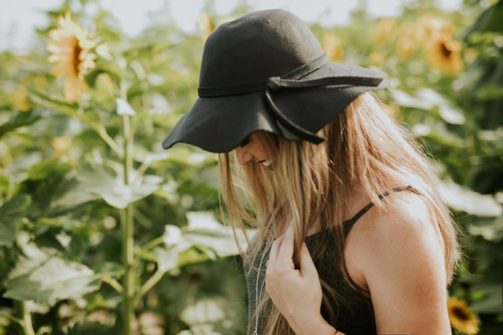 gorgeous woman in black floppy hat walks through sunflower pictures at tuttle orchard