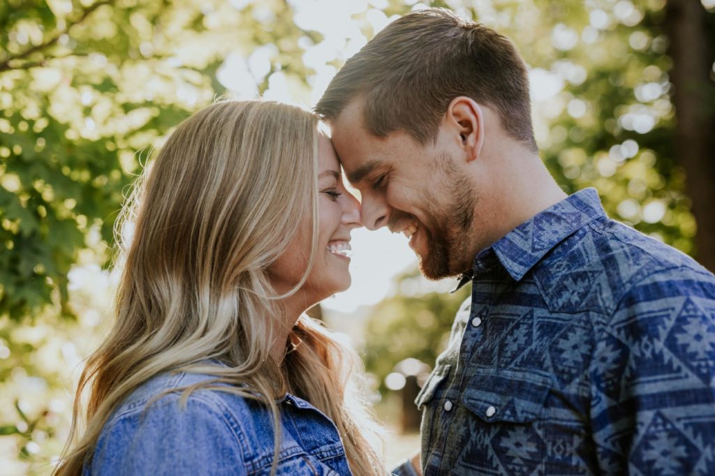 man and woman touch foreheads and laugh in the woods during their Eagle Creek Engagement Photos