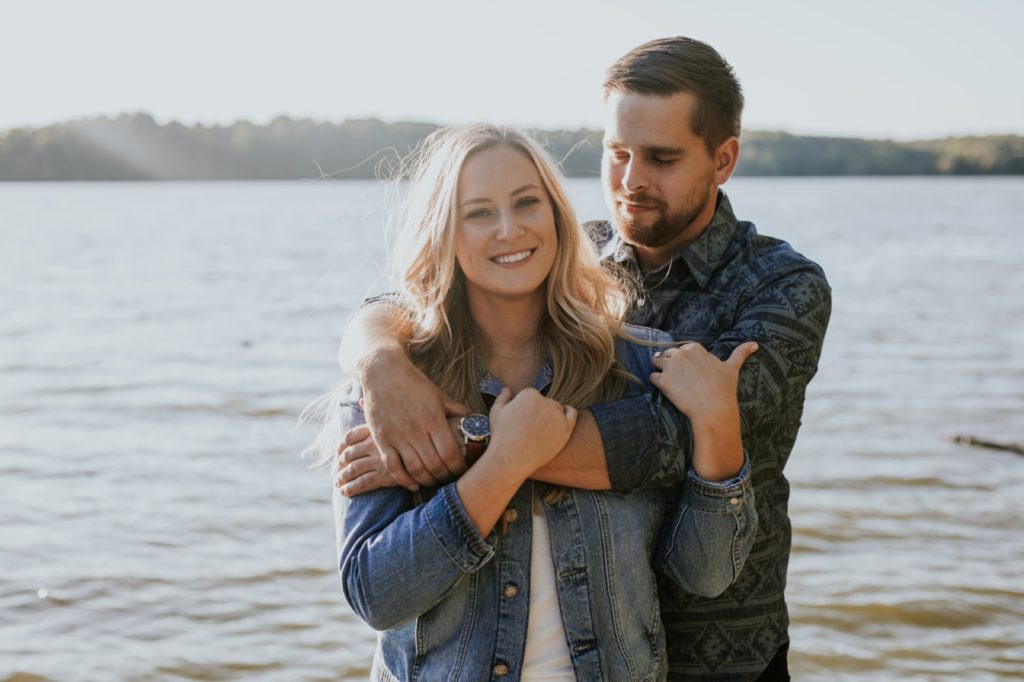 a man and a woman hug on a dock during their Eagle Creek Engagement Photos