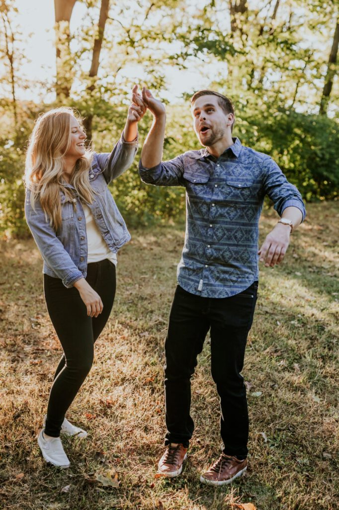 a blonde woman spins a man while dancing during their Eagle Creek Engagement Photos