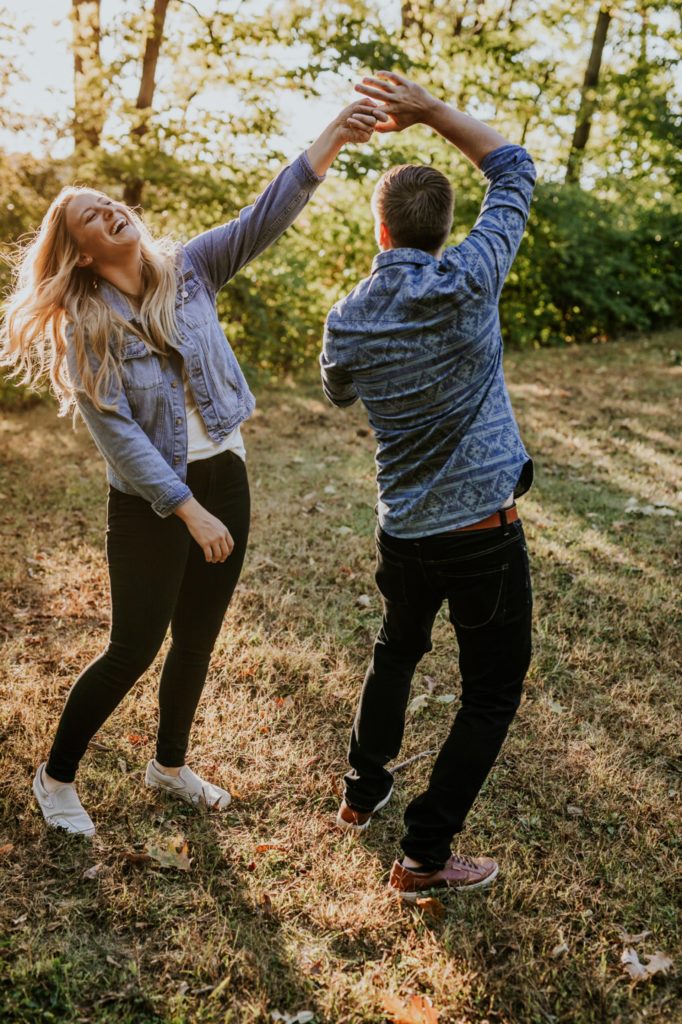 a blonde woman laughs uproariously while spinning a man during their Eagle Creek Engagement Photos