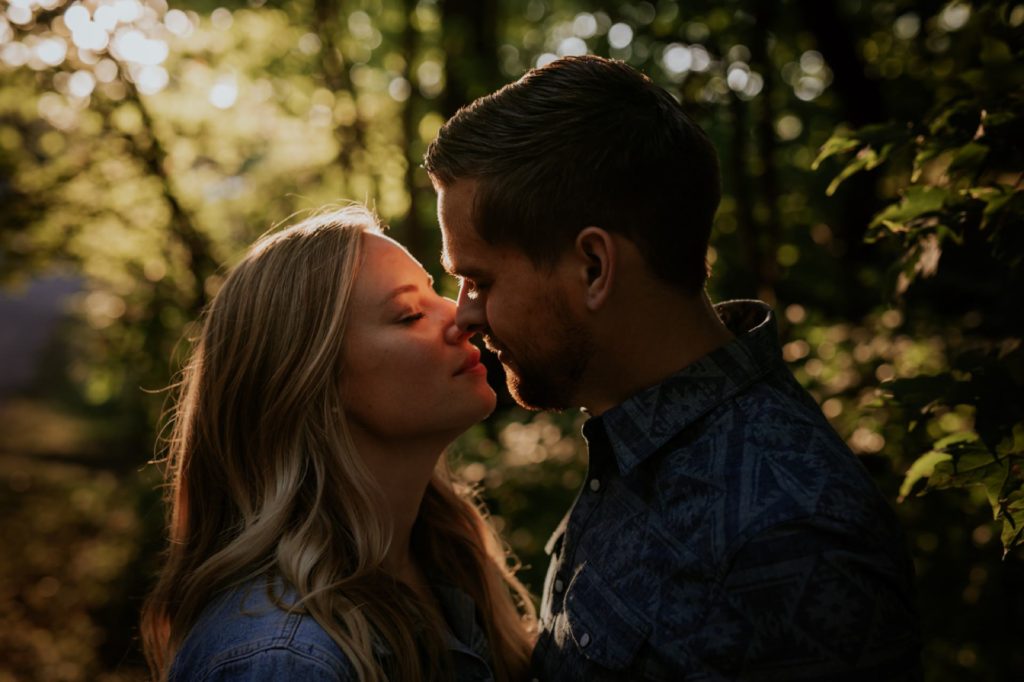 a dark and moody photo of a man and woman kissing during their Eagle Creek Engagement Photos