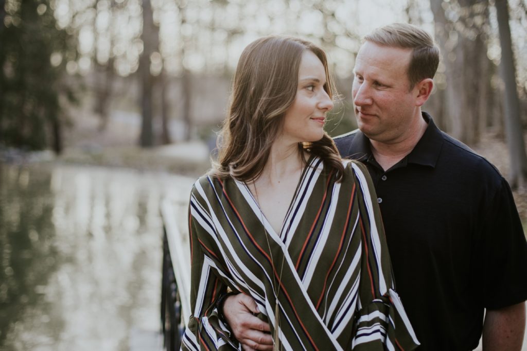 a man and a woman look at each other lovingly during their holcomb gardens winter engagement shoot