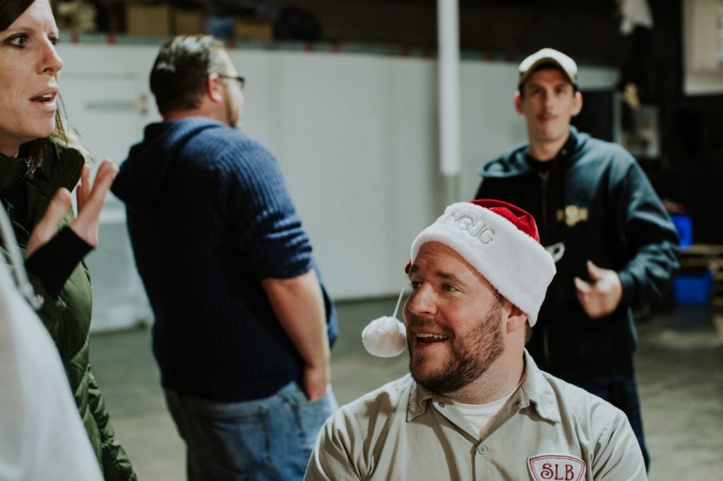 director and brewer joshua hull in christmas hat at an herst with scarlet lane brewing company logo on back at this Indianapolis Brewery Event Photography