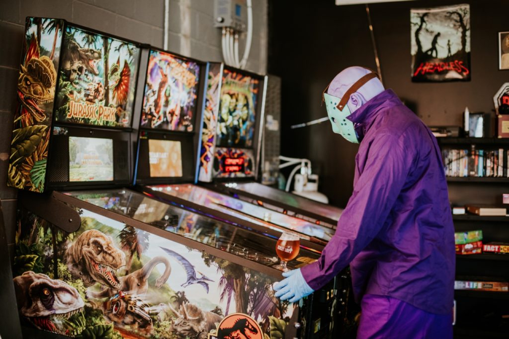 man in purple jumpsuit with purple skin and hockey mask plays pinball in this Indianapolis brewery photography