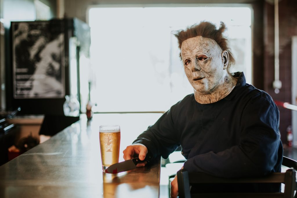 man with leathery face holds knife to beer in this Indianapolis brewery photography