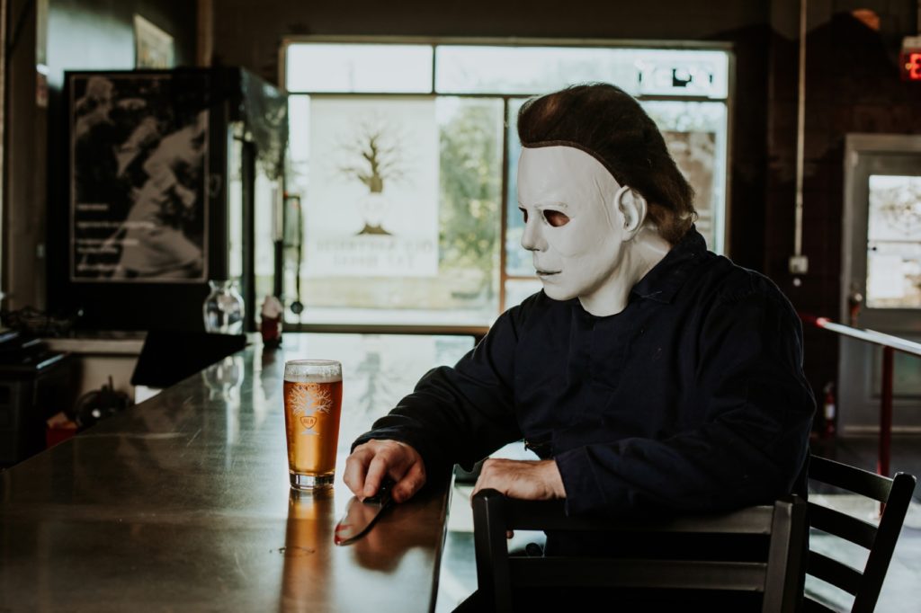 man with white face mask on drinks a beer at the bar at scarlet lane brewery in this Indianapolis brewery photography