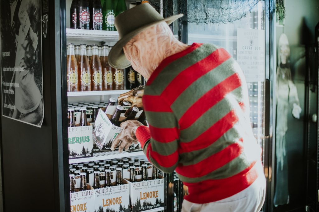 stripey shirt guy grabs a beer out of the refrigerator at scarlet lane