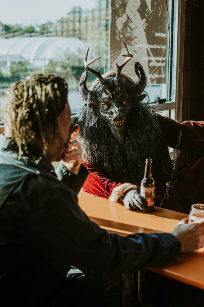 krampus and halloween masked man share beers