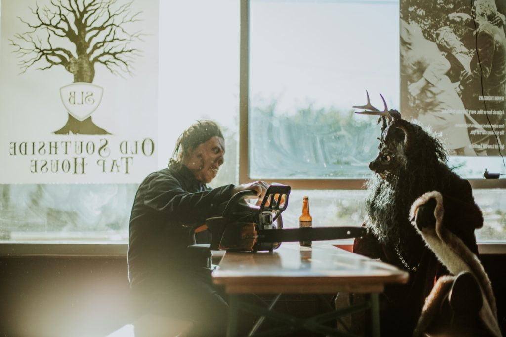 krampus and man in halloween mask drink beer in front of large windows for this Indianapolis brewery photography