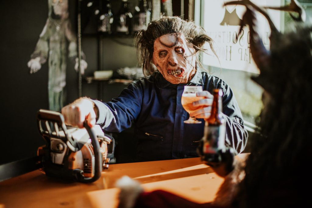 man in halloween mask with chainsaw drinks a beer at scarlet lane for this Indianapolis brewery photography