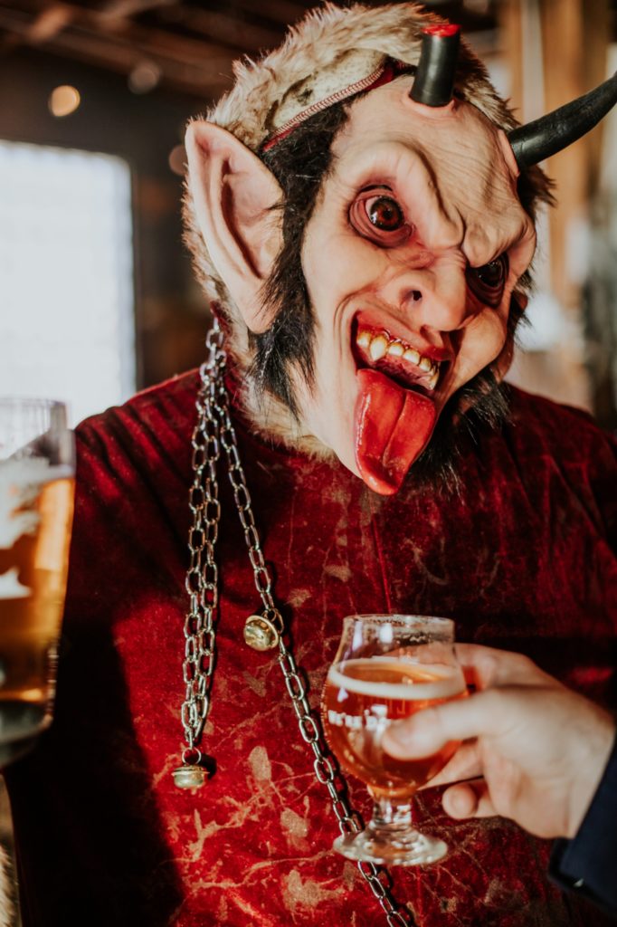 man dressed like a devil licks beer out of glass at an indy brewery