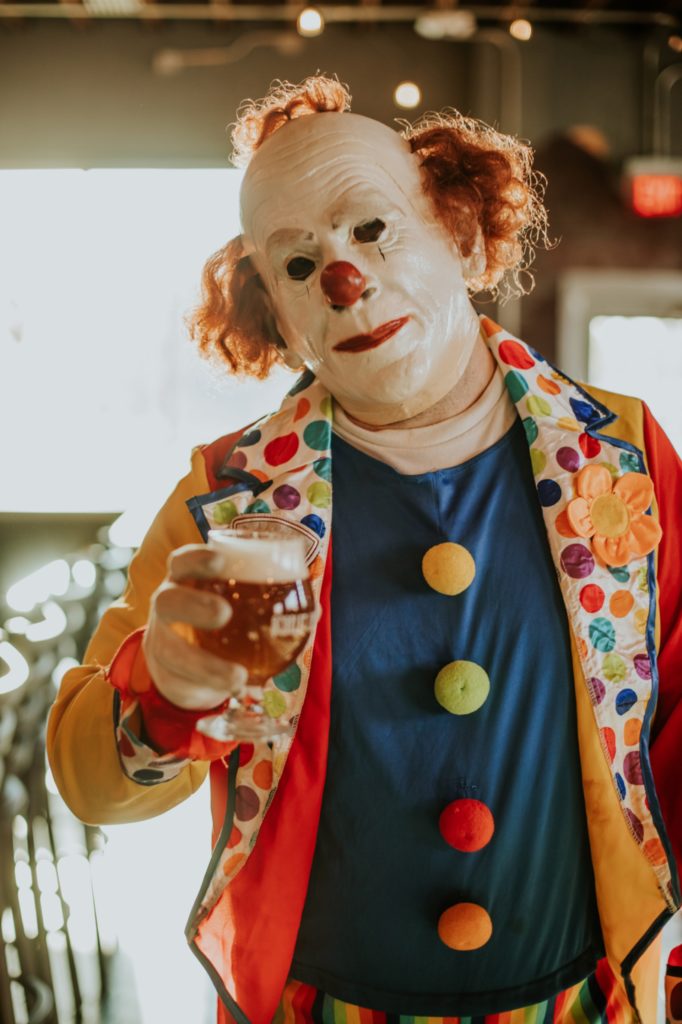 clown holds a beer out for consumption in this Indianapolis brewery photography
