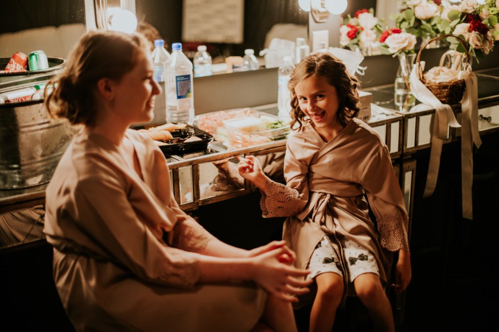 flower girls laugh and smile while getting ready at an industrial wedding venue in indianapolis