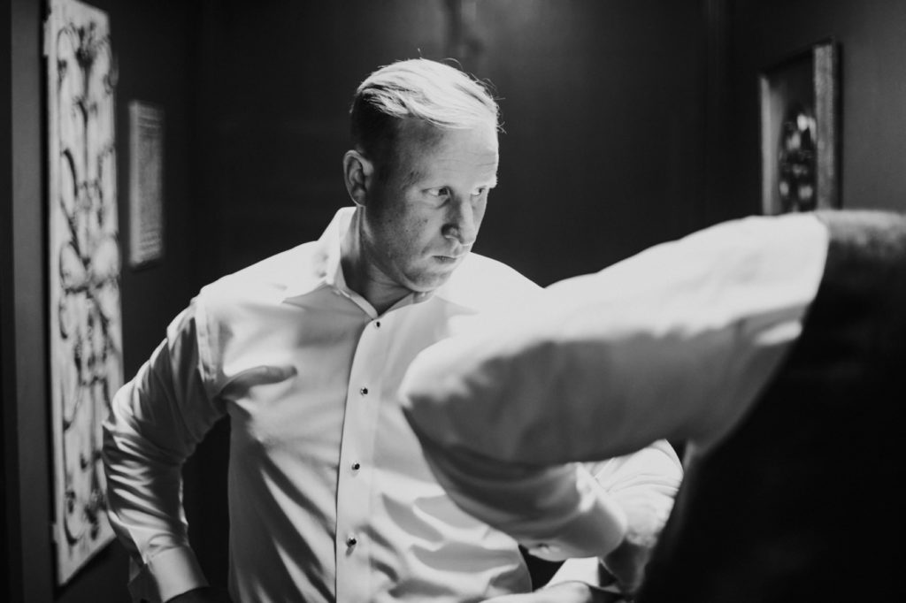 black and white photo of groom getting ready at an industrial wedding venue