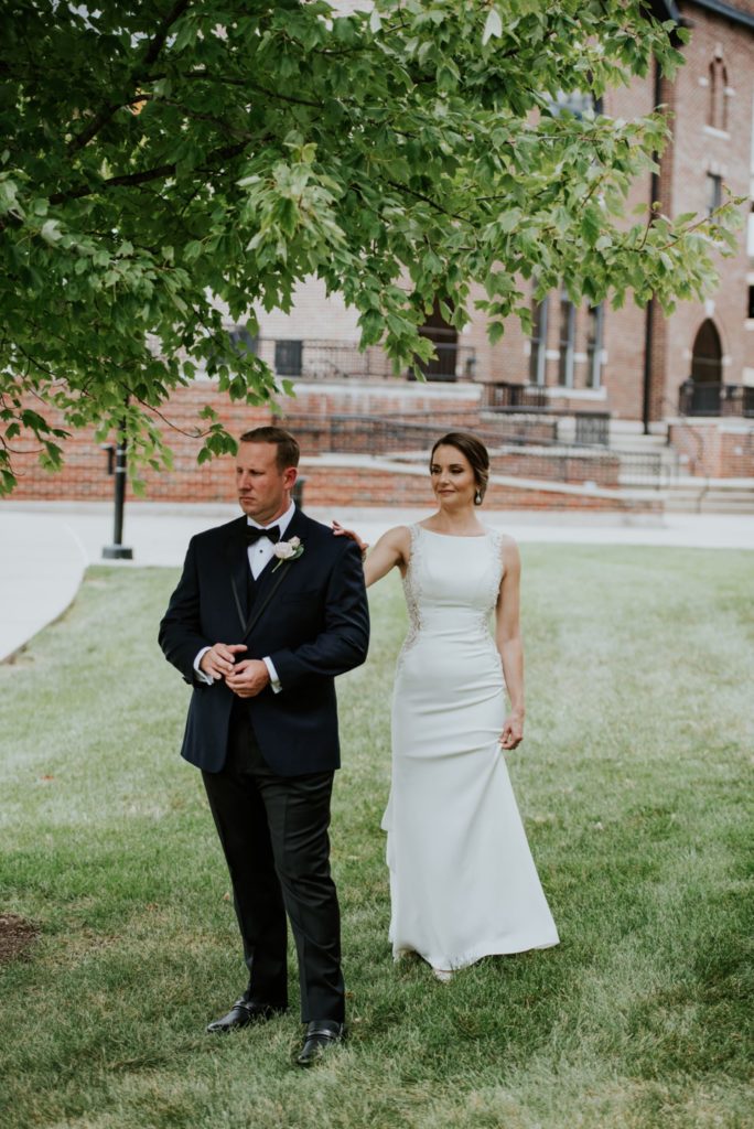 bride taps groom on the shoulder during first look at indianapolis canal