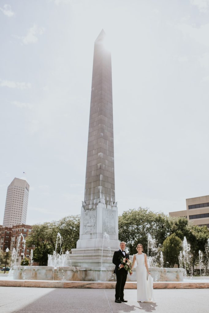 bride and groom standing in sunlight at obelisk square